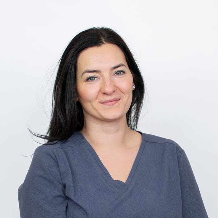 Zdjęcie profilowe weterynarz zajmującej się dermatologią i otologią psów i kotów. Lekarka delikatnie przekrzywiła głowę i uśmiecha się do aparatu, ma ubrany szary fartuch weterynaryjny.